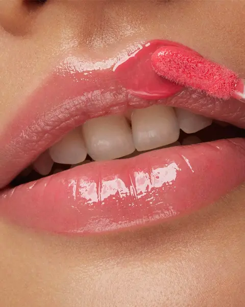 Gloss Kiko Bridgerton Brilliant Bliss Lip Gloss 02 Blushing Nectarine aplicando a cor nos lábios, com um tom suave de nectarina.